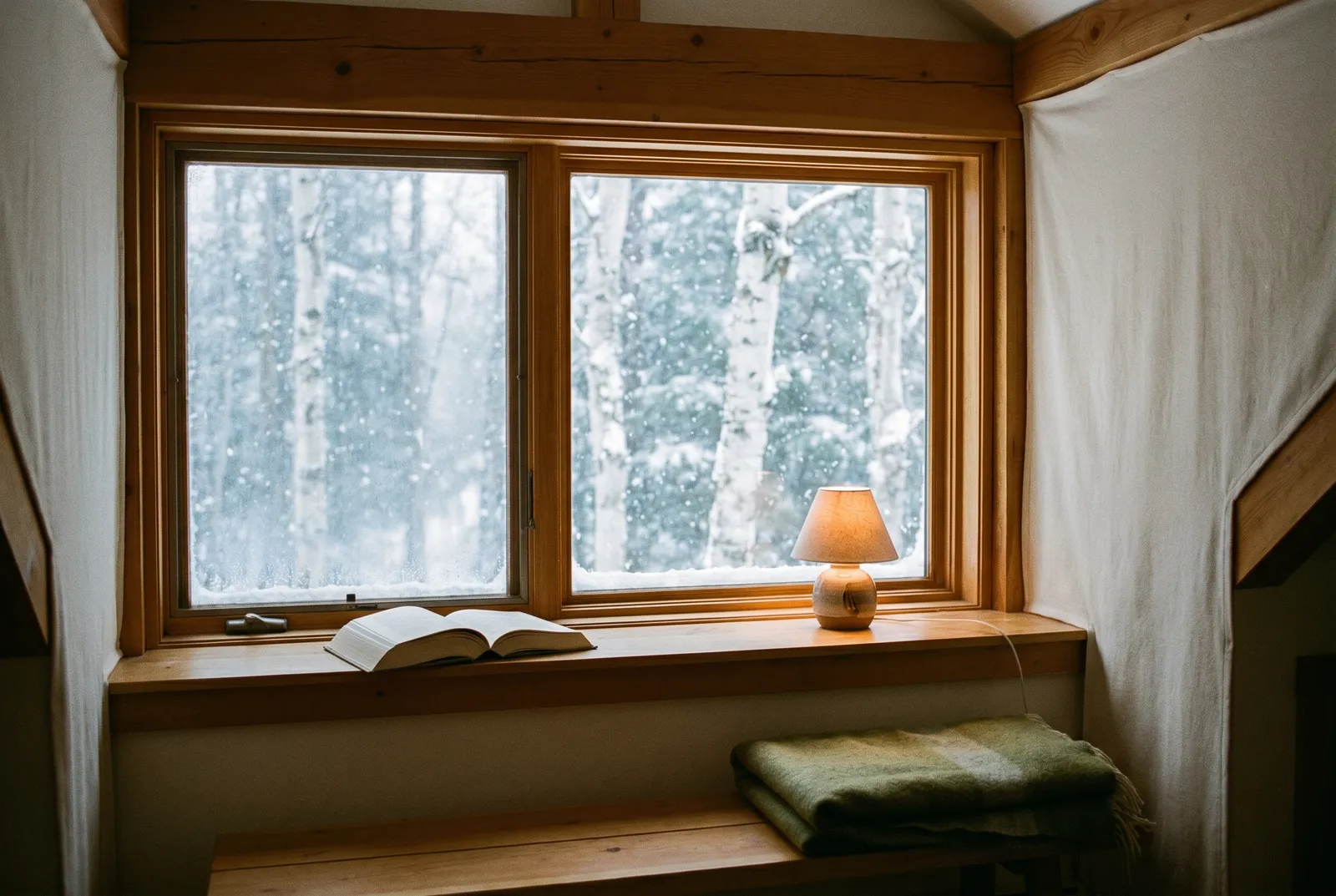 木の窓辺、雪景色と本とランプ